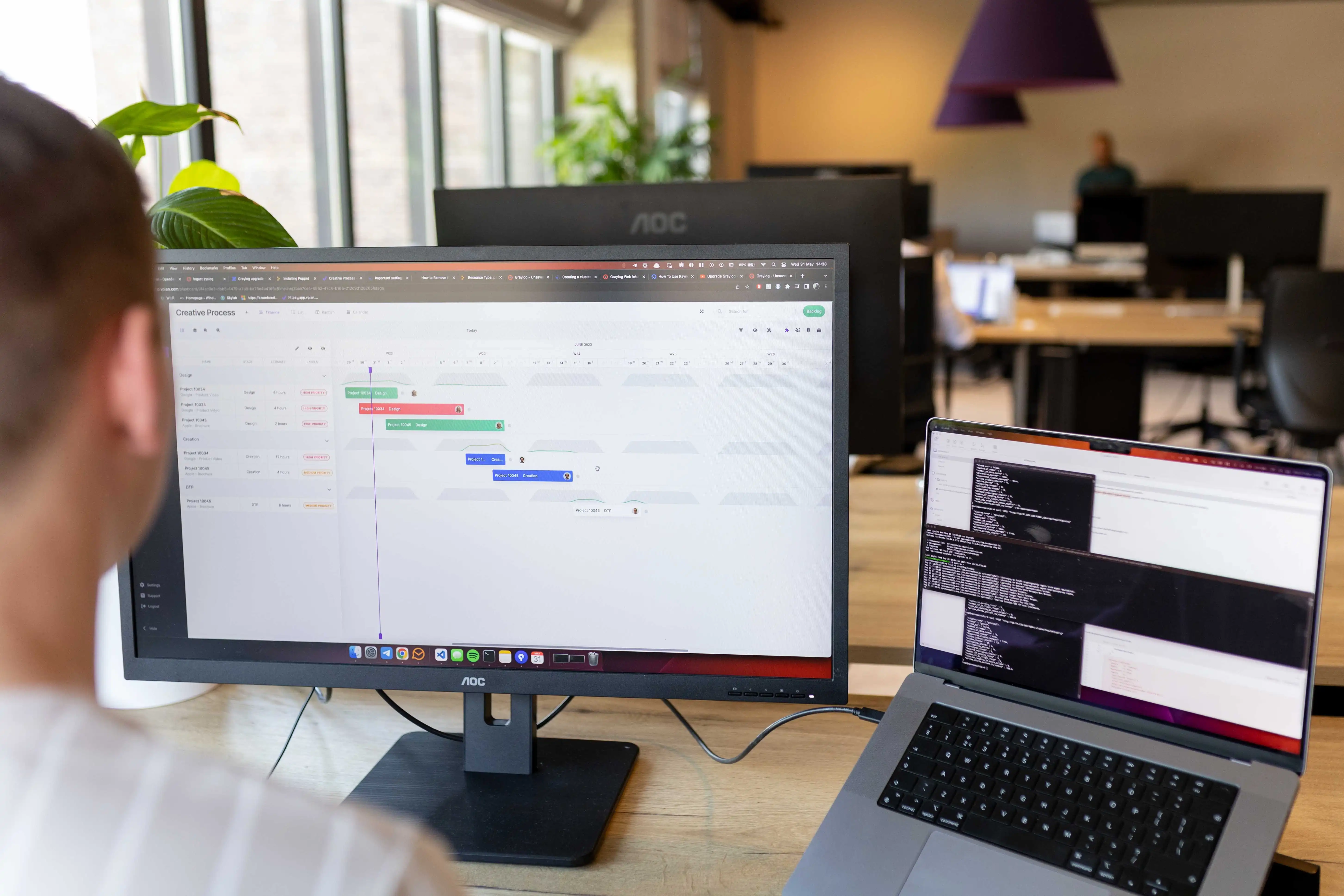Een man die een laptop en een extra scherm heeft, waarop je de planning tool van vPlan ziet waarmee hij aan het programmeren is.